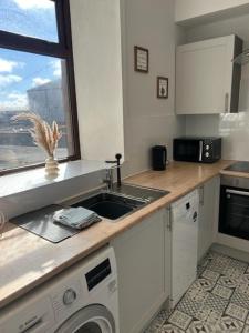 a kitchen with a sink and a washing machine at Class Apartments in Peterhead