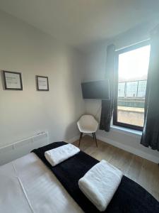 a bedroom with a bed with a chair and a window at Class Apartments in Peterhead