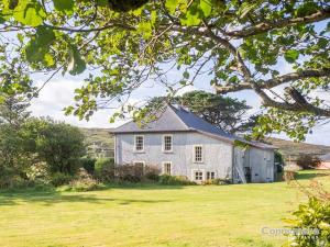 a white house in a field with a tree at Kill House, Kingstown in Clifden