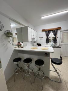 a kitchen with three bar stools at a counter at Maresea rooms in Larnaka