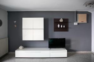 Una sala de estar con un televisor en una pared azul. en IseoLakeRental - Casa Angelica, en Riva di Solto