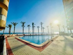 a swimming pool next to the beach with palm trees at La Manga apartamento Siesta in San Blas