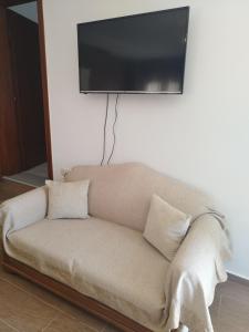 ein Sofa mit einem Flachbild-TV an der Wand in der Unterkunft ΚΛΕΟΠΑΤΡΑ in Sfendámion
