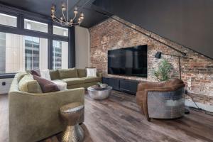 a living room with a brick wall and a television at Penthouse Grand Executive Suite in Louisville