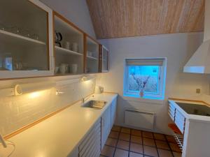 a white kitchen with a sink and a window at Holiday home in resort in Skagen with public pool in Skagen