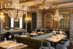 a restaurant with tables and chairs and chandeliers at Château St Gerlach - Oostwegel Collection, member of Relais and Châteaux in Valkenburg