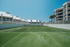 a tennis court in front of a building at Ground floor beachfront with steps to the beach and pool & beach access in New Smyrna Beach