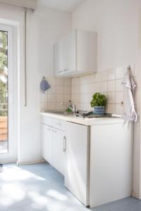 una cocina blanca con armarios blancos y fregadero en Pension Krone en Schwäbisch Gmünd