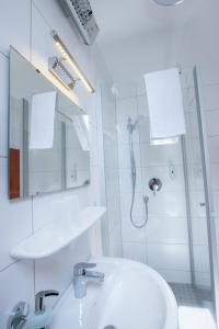 a white bathroom with a sink and a shower at Pension Krone in Schwäbisch Gmünd