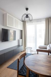 a living room with a table and a tv at Apartament Sztutowo by Ski and Sea in Sztutowo