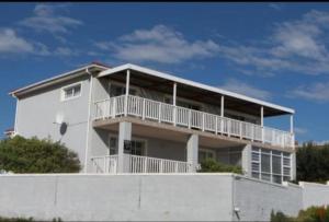 a white house with a balcony on top of it at Bay Haven in Gansbaai