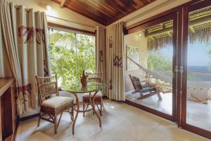 a dining room with a table and chairs and a balcony at Hotel Ponta do Madeiro in Pipa