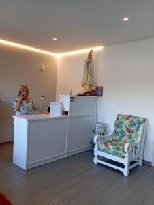 a woman sitting at a counter in a room with a chair at Casa Talika in Fátima