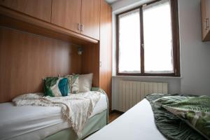 Un dormitorio pequeño con dos camas y una ventana. en IseoLakeRental - Casa Angelica, en Riva di Solto
