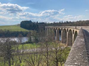 a bridge over a river next to a road at Maison proche de la Loire in Saint-Georges-de-Baroille