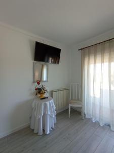 Habitación blanca con mesa y TV en la pared en Casa Talika, en Fátima