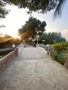 a bridge over a body of water with trees at Akkas Farm House in Faisalabad