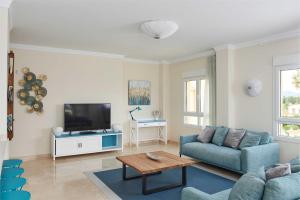 uma sala de estar com um sofá azul e uma televisão em Bogey by Oliva Nova em Oliva