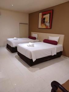 Dos camas en una habitación de hotel con toallas. en 3 Putra BI Executive Hotel Jakarta en Yakarta