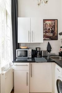 a kitchen with white cabinets and a microwave at Studio an der Therme in Baden-Baden