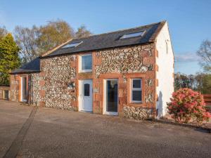 an old brick building with a white door and windows at Criffel Cottage in Ruthwell