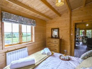 ein Schlafzimmer mit einem Bett in einer Holzhütte in der Unterkunft Stable Lodge At Greenacre in Bromyard