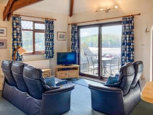 a living room with chairs and a television and a balcony at Marine Mews 3 in Salcombe
