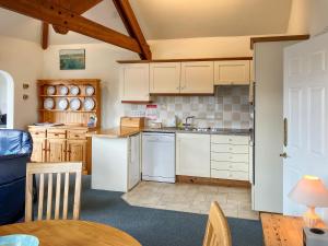 a kitchen with white cabinets and a table and chairs at Marine Mews 3 in Salcombe