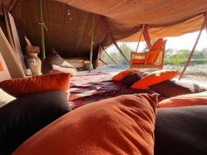 a bed in a tent with pillows on it at Le Khaïma Bio, Oasis écologique au bord de l'océan in Douaïra