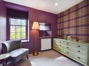 a bedroom with purple walls and a chair and a dresser at Moncrieff House in Falkland