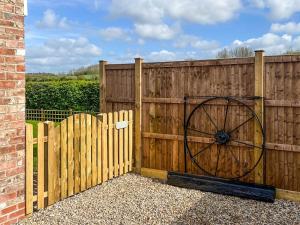 a wooden fence with a large wooden wheel on it at Cartwheel Cottage in Hayton