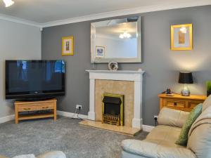 a living room with a tv and a fireplace at Garden Cottage in Nafferton