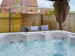 a jacuzzi tub with chairs and an umbrella at Garden Cottage in Nafferton