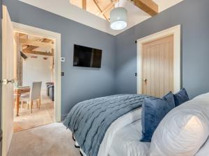 a bedroom with blue walls and a bed and a table at Cattle Cake Cottage in Askham