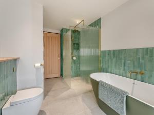 a bathroom with a tub and a shower and a toilet at Cattle Cake Cottage in Askham