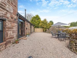 a patio with a table and chairs and an umbrella at Cattle Cake Cottage in Askham