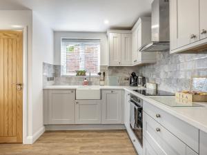 a kitchen with white cabinets and a sink and a window at Fallows Holt in Buildwas