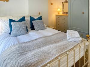 a bed with blue and white pillows and a dresser at Rectory Cottage - Uk46995 in Overstrand