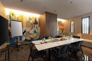 einen Konferenzraum mit einem Tisch, Stühlen und einem Bildschirm in der Unterkunft Hyatt Centric Jumeirah - King Room Sea View - UAE in Dubai