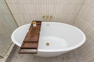 a white bath tub in a bathroom with a wooden table at Modern Mid Century Getaway. Luxury by Hollyhock in Louisville
