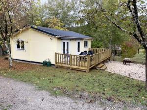mały biały dom z werandą na dziedzińcu w obiekcie Camping Le Convivial w mieście Foncène