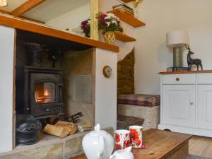 uma sala de estar com um fogão a lenha e uma mesa em Hebble Row Cottage em Oakworth