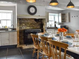 una cucina con tavolo, sedie e camino di Box Tree Farmhouse - Uk47034 a Kirkby Lonsdale