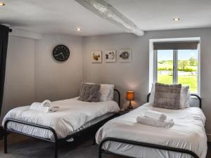 2 camas en una habitación con un reloj en la pared en Box Tree Farmhouse - Uk47034 en Kirkby Lonsdale