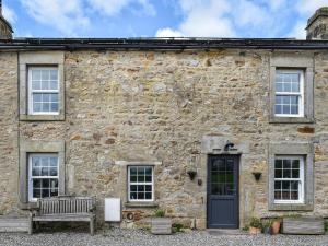 un edificio de piedra con un banco delante en Box Tree Farmhouse - Uk47034 en Kirkby Lonsdale