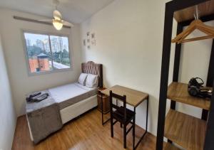 Cette petite chambre comprend un lit, un bureau et une fenêtre. dans l'établissement Por do sol desde uma rede na varanda da zona sul, à São Paulo