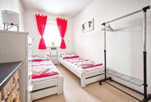 - 2 lits dans une chambre dotée de rideaux rouges dans l'établissement Penzion bazén víno sklep U Palečků, à Zaječí