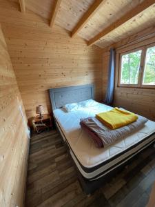 łóżko w drewnianym pokoju w kabinie w obiekcie Camping Le Convivial w mieście Foncène