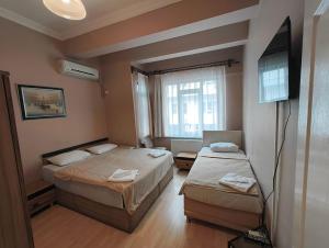 a hotel room with two beds and a television at Tac Pansiyon in Edirne