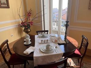 uma mesa de jantar com um vaso de flores em Palacete da Real Companhia do Cacau - Royal Cocoa Palace em Montemor-o-Novo